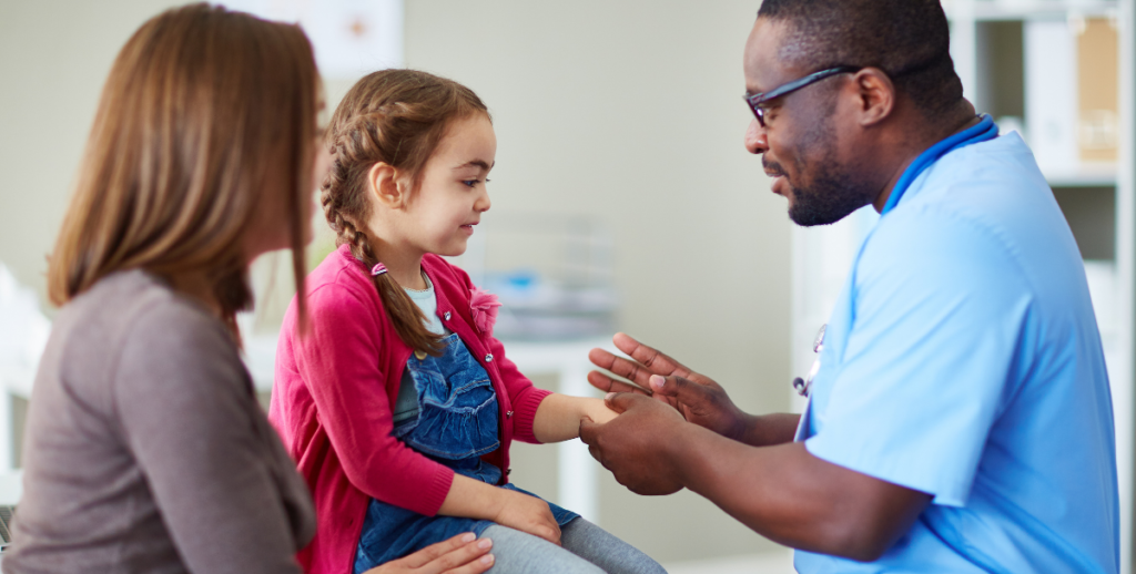 Medical doctor examining a child with parent looking on.